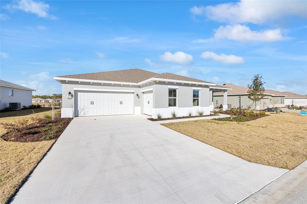 A single-story house with a gray exterior, white trim, and a three-car garage — 9918 SW 106TH CIRCLE, OCALA, FL