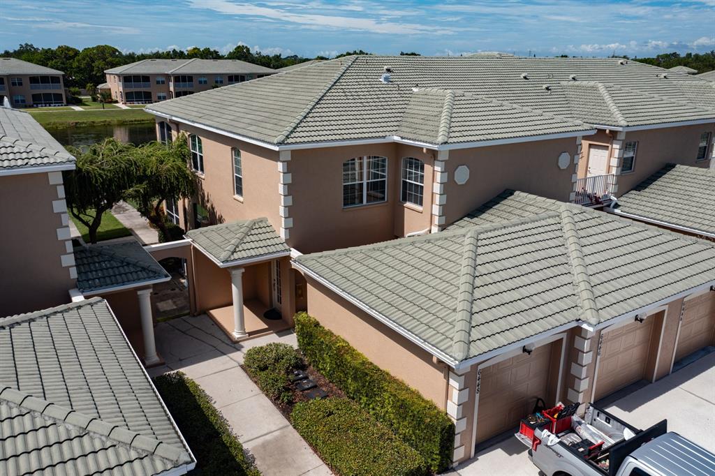 An aerial view shows the exterior of a tan two-story townhouse with a tiled roof — 6448 7TH AVENUE CIRCLE W, BRADENTON, FL