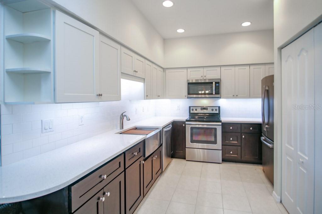 A kitchen features white upper cabinets, dark lower cabinets, white countertops, and stainless steel appliances — 6448 7TH AVENUE CIRCLE W, BRADENTON, FL