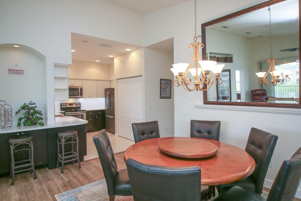 A dining area with a round wooden table, leather chairs, and a large wall mirror — 6448 7TH AVENUE CIRCLE W, BRADENTON, FL