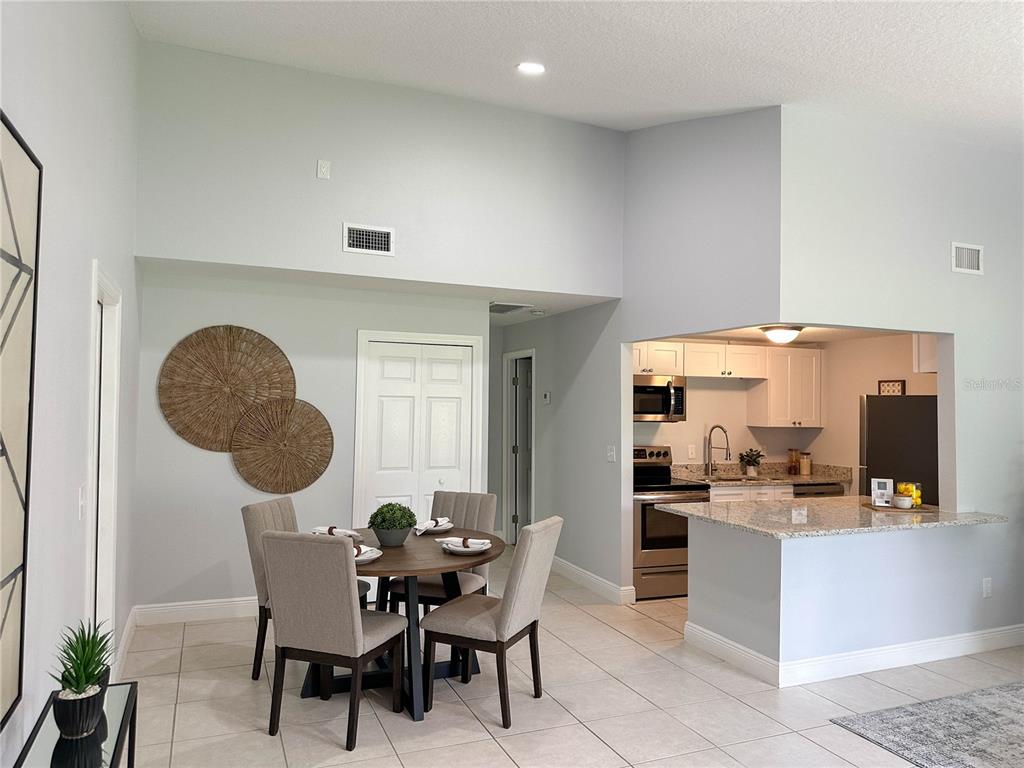 A dining area with a round table and chairs sits adjacent to an open kitchen — 23 COUNTRY CLUB DRIVE UNIT B, NEW SMYRNA BEACH, FL