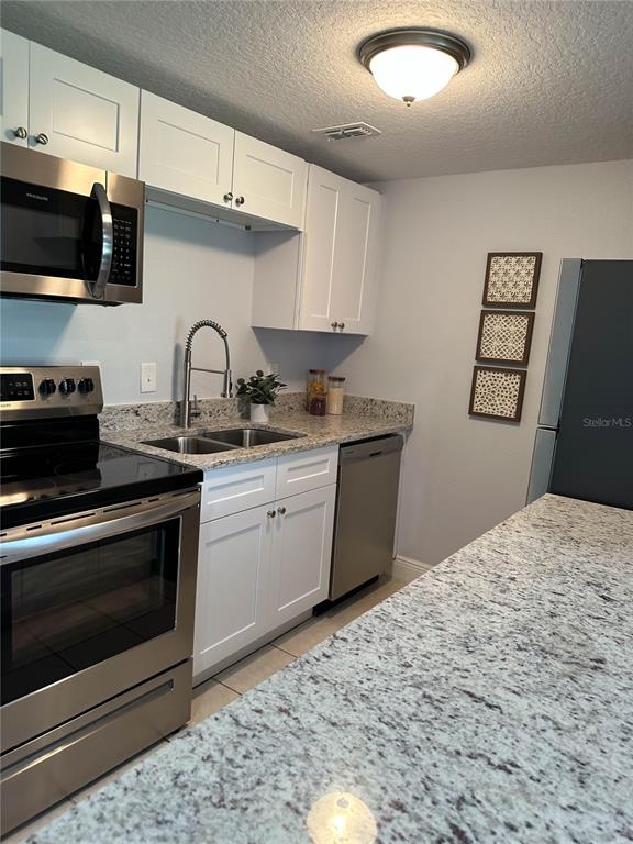 A kitchen features white cabinets, granite countertops, stainless steel appliances, and a double-basin sink — 23 COUNTRY CLUB DRIVE UNIT B, NEW SMYRNA BEACH, FL