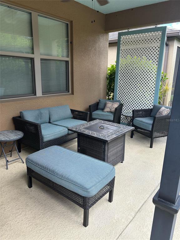 A covered patio features wicker furniture, a fire pit table, and a white lattice privacy screen — 221 ALMERIA WAY, DAVENPORT, FL