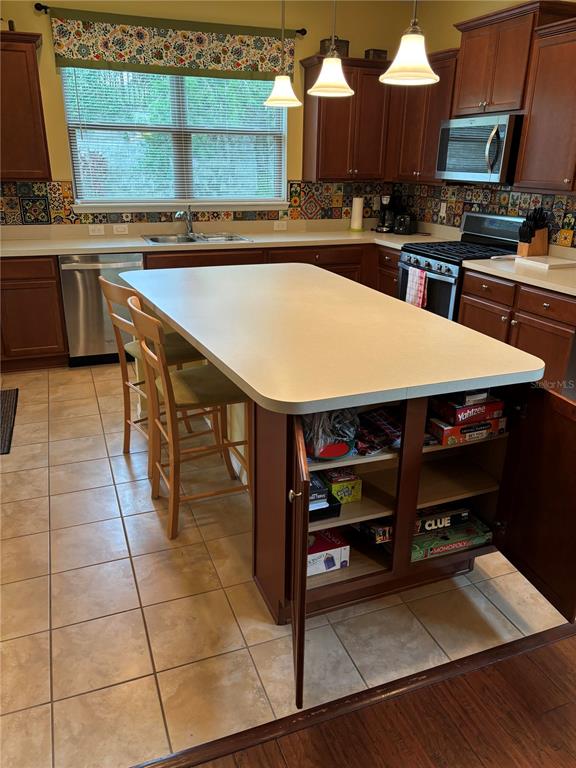 A kitchen features a central island with open shelving, wooden cabinets, and a tiled backsplash — 221 ALMERIA WAY, DAVENPORT, FL