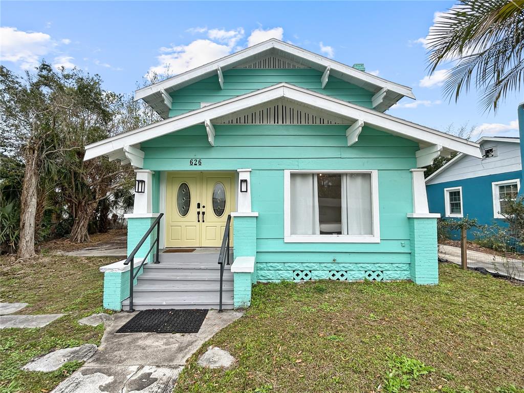 A turquoise bungalow with a front porch, yellow double doors, and a concrete walkway — 626 37TH AVENUE S, ST PETERSBURG, FL