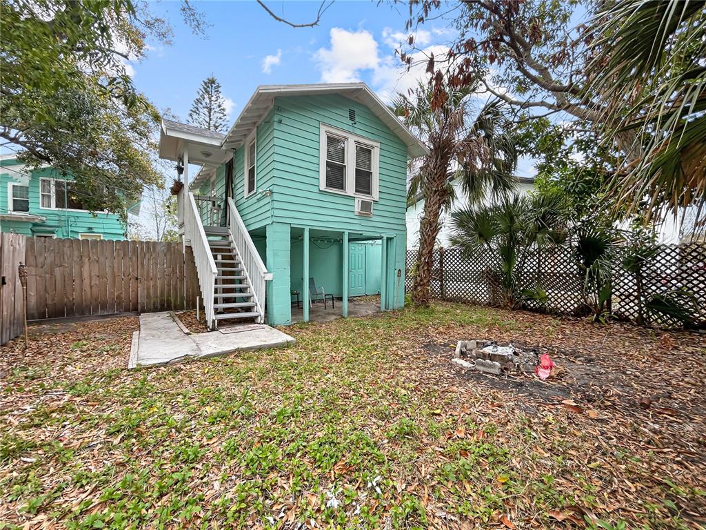 A light green elevated house with an exterior staircase stands in a leaf-covered yard — 626 37TH AVENUE S, ST PETERSBURG, FL