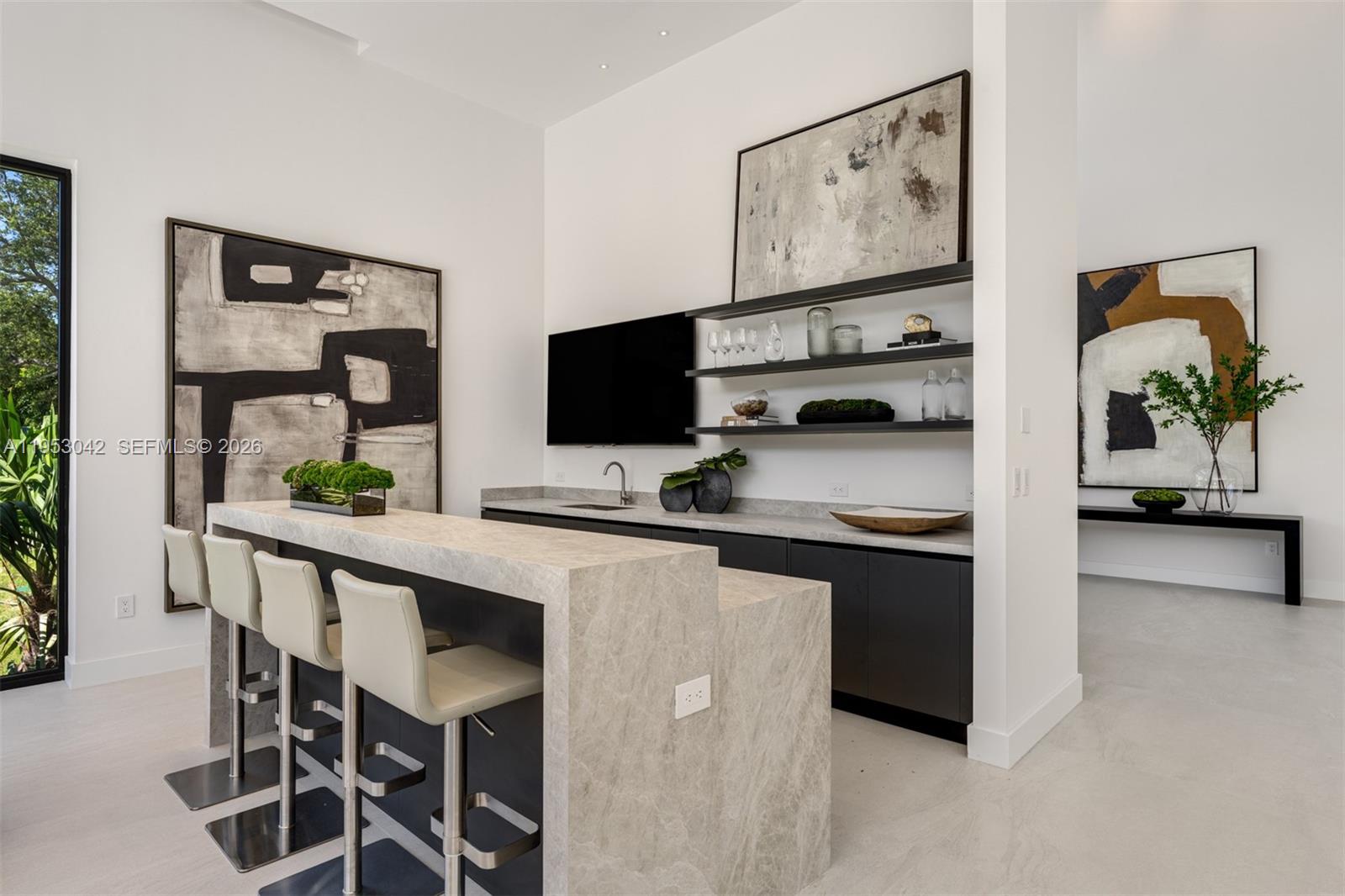 A modern open-concept living room and kitchen feature a large sectional sofa and neutral finishes — 5825 SW 111th Ter, Pinecrest FL 33156, PINECREST, FL