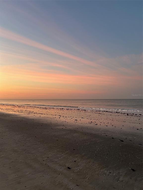 A view of a sandy beach at sunset with calm ocean waves meeting the shore — 18218 SUNSET BOULEVARD UNIT B, ST PETERSBURG, FL