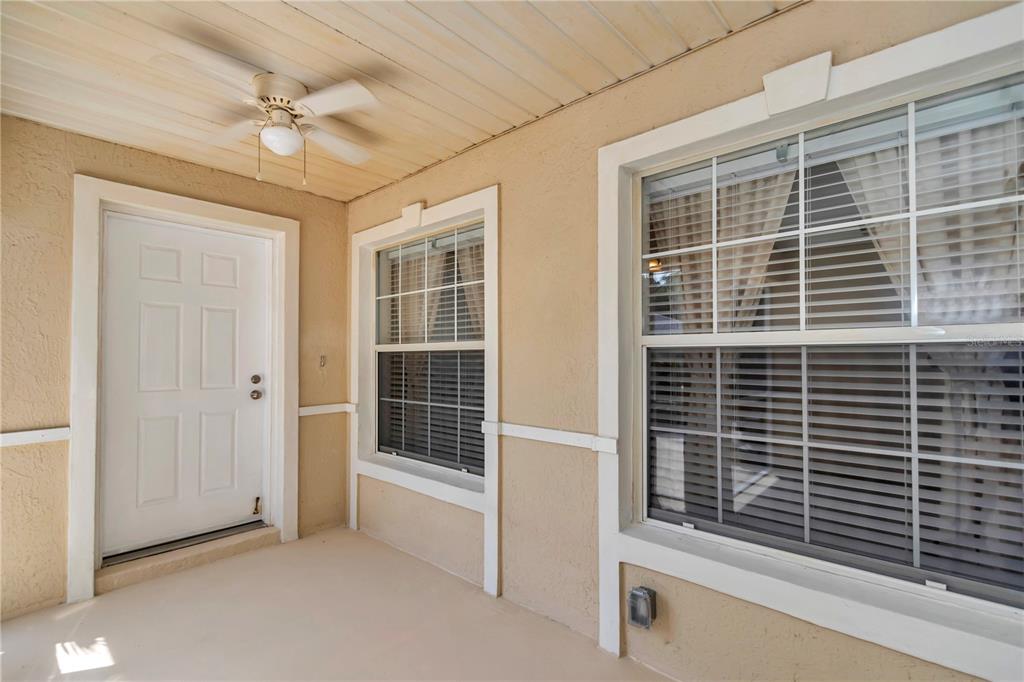 A covered patio features a white door, two windows with blinds, and a ceiling fan — 7229 SW 115TH PLACE, OCALA, FL