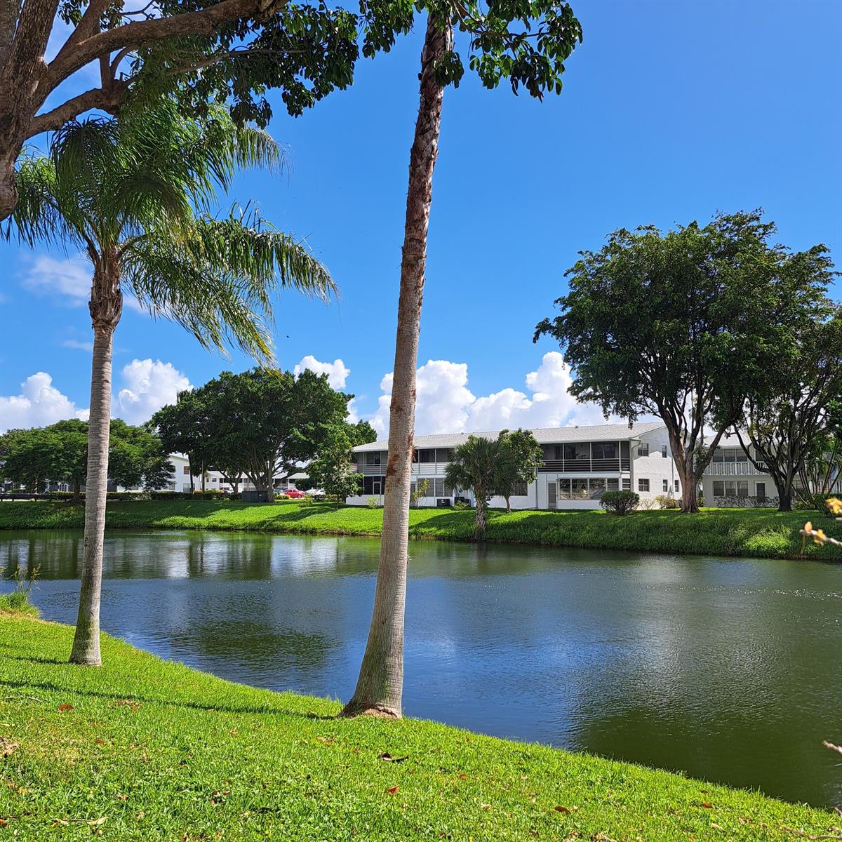 A pond sits in front of a two-story apartment building surrounded by trees and grass — 53 Northampton C, West Palm Beach FL 33417, WEST PALM BEACH, FL