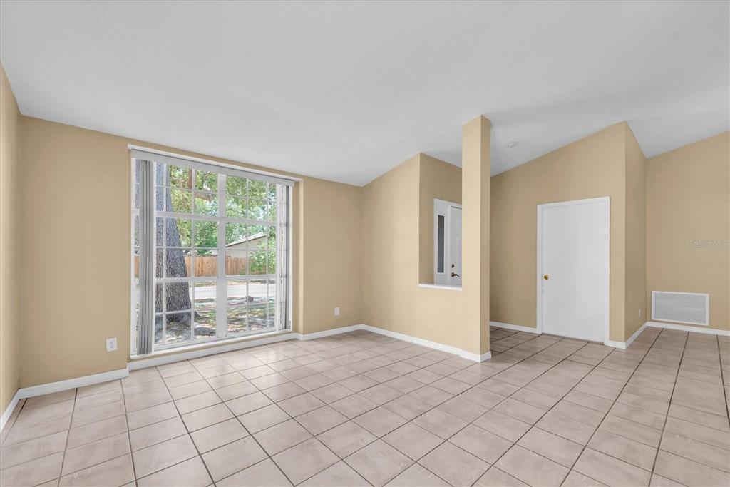 An empty room with beige walls, light-colored tile flooring, and a large window — 4704 LIGHTERWOOD WAY, VALRICO, FL