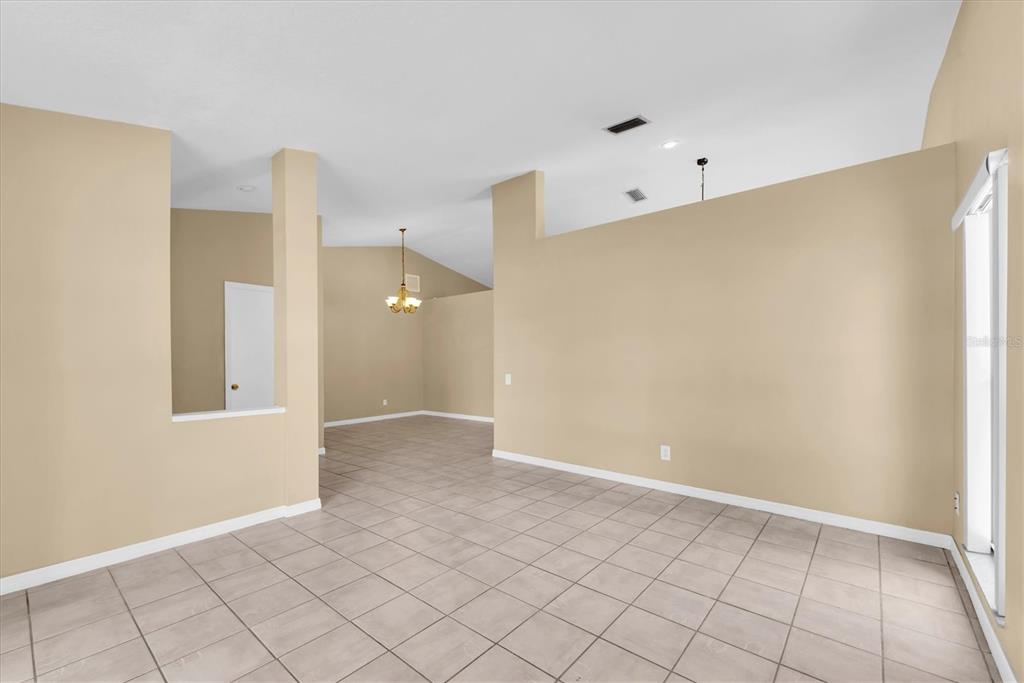 An empty room with beige walls, tile flooring, and a vaulted ceiling — 4704 LIGHTERWOOD WAY, VALRICO, FL