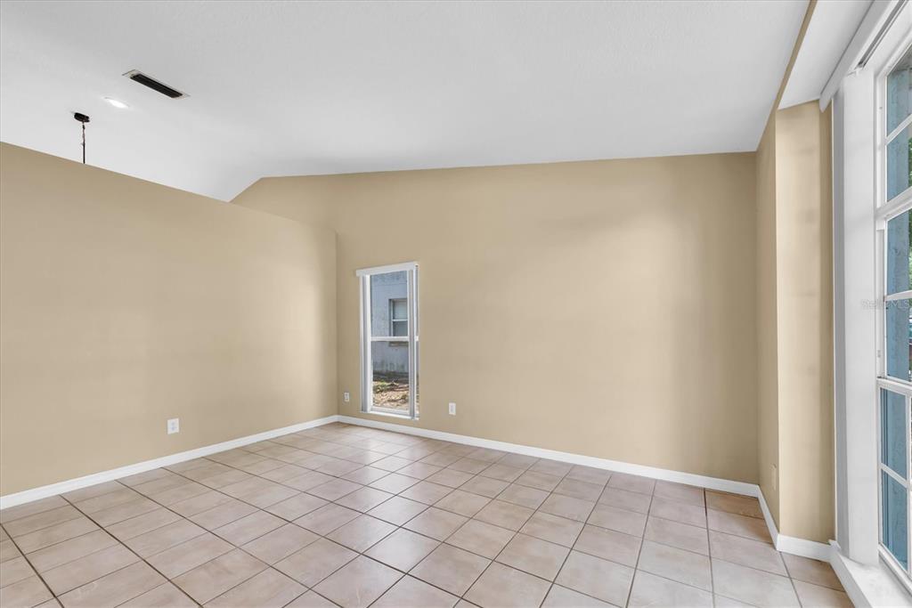 An empty room features beige walls, light-colored tile flooring, and a vaulted ceiling — 4704 LIGHTERWOOD WAY, VALRICO, FL
