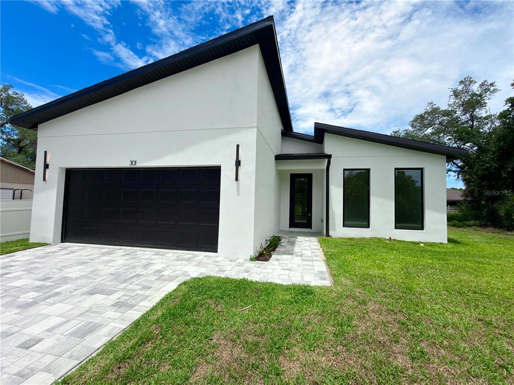 A modern white house with a black garage door and black window frames — 301 EPPINGER DRIVE, PORT CHARLOTTE, FL