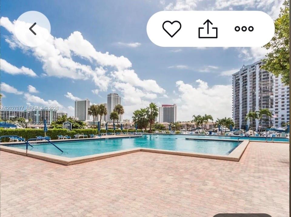 A swimming pool with a paved deck overlooks a marina and high-rise buildings — 600 Three Islands Blvd # 312, Hallandale Beach FL 33009, HALLANDALE BEACH, FL