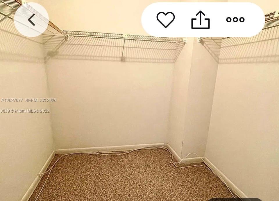 A small walk-in closet features beige carpeting, white walls, and wire shelving — 600 Three Islands Blvd # 312, Hallandale Beach FL 33009, HALLANDALE BEACH, FL