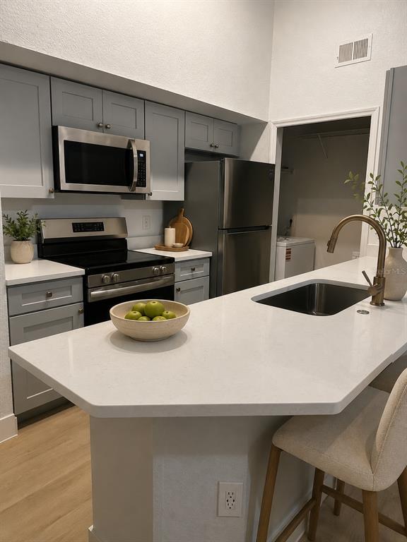 A kitchen features gray cabinets, stainless steel appliances, white countertops, and a breakfast bar — 13016 PLANTATION PARK CIRCLE UNIT 1131, ORLANDO, FL