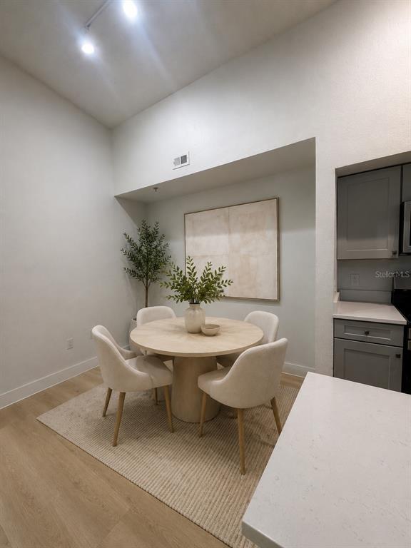 A dining area features a round table with four chairs on a rug near a kitchen — 13016 PLANTATION PARK CIRCLE UNIT 1131, ORLANDO, FL