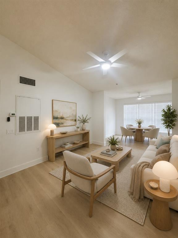 A bright living room features light wood flooring, neutral furniture, and a dining area beyond — 13016 PLANTATION PARK CIRCLE UNIT 1131, ORLANDO, FL
