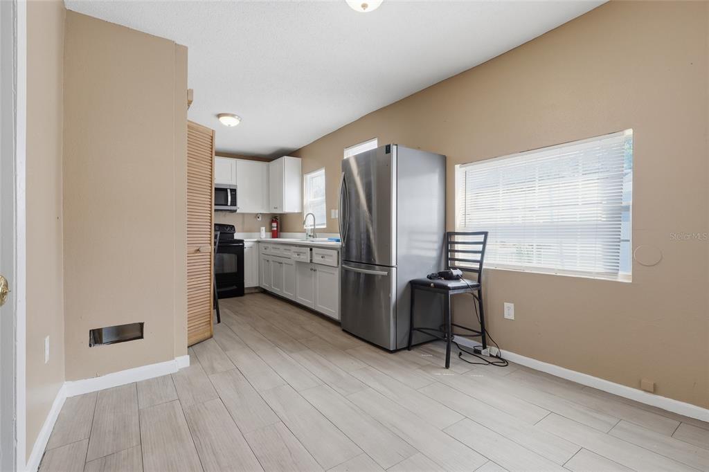 A kitchen features white cabinets, stainless steel appliances, and light wood-look tile flooring — 920 E ANNIE STREET, TAMPA, FL
