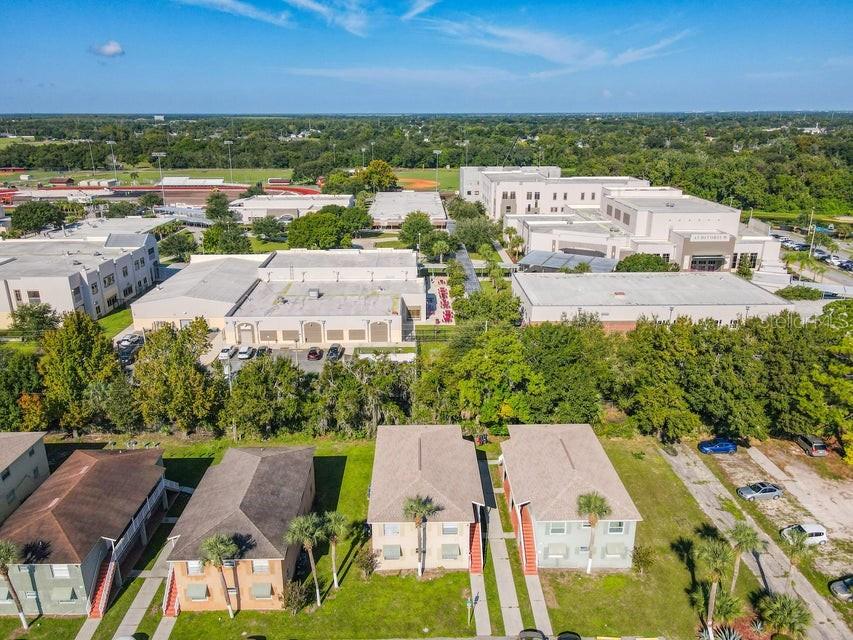 An aerial view shows residential buildings in the foreground and a large school complex behind — 714 MICHIGAN COURT UNIT 1, 2, 3 and 4, ST CLOUD, FL
