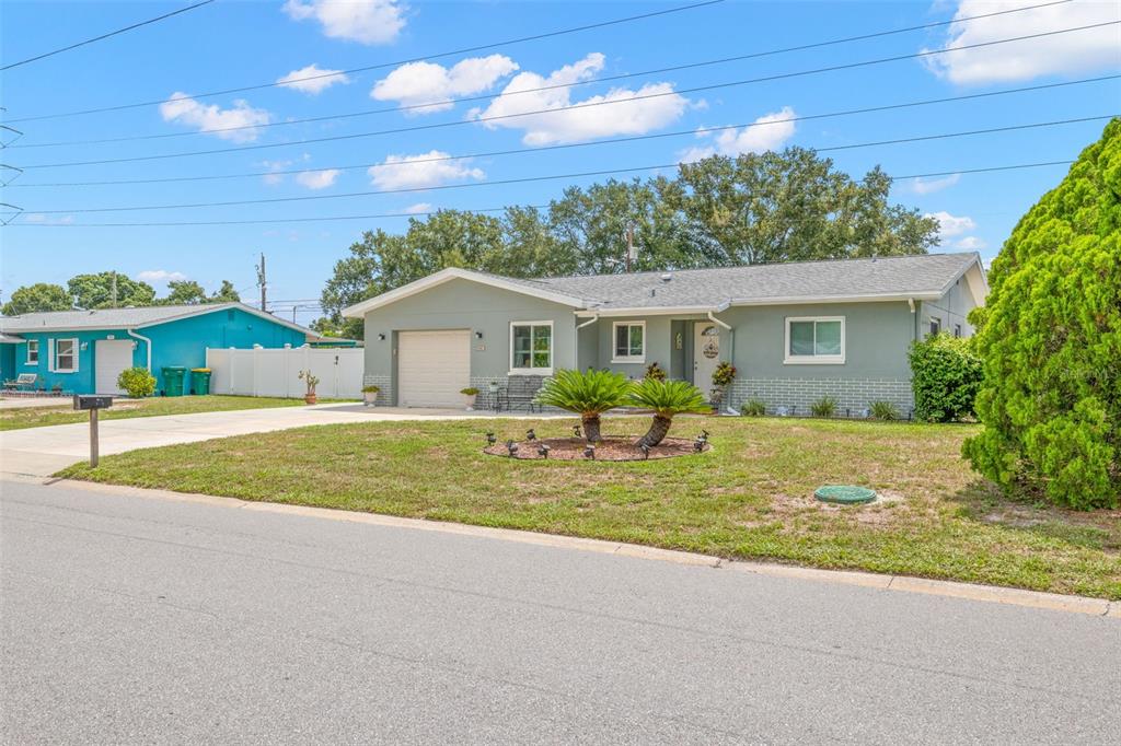 A single-story house with a light green exterior, a garage, and a front lawn — 29861 69TH STREET N, CLEARWATER, FL