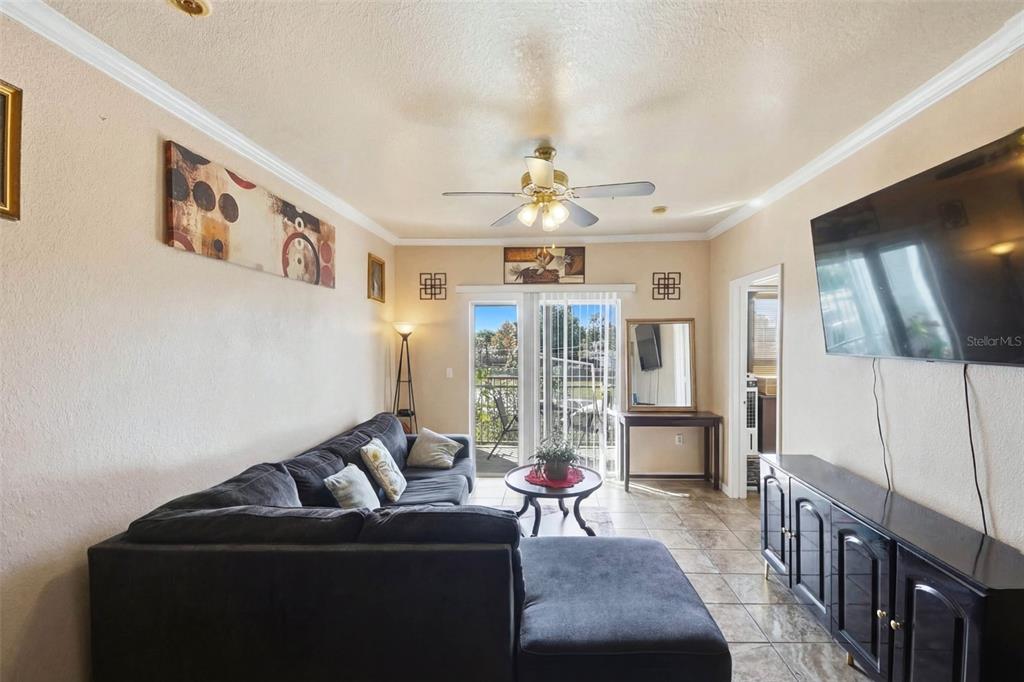 An empty room with gray walls, tile flooring, a ceiling fan, and a sliding glass door — 5526 PGA BOULEVARD UNIT 4927, ORLANDO, FL