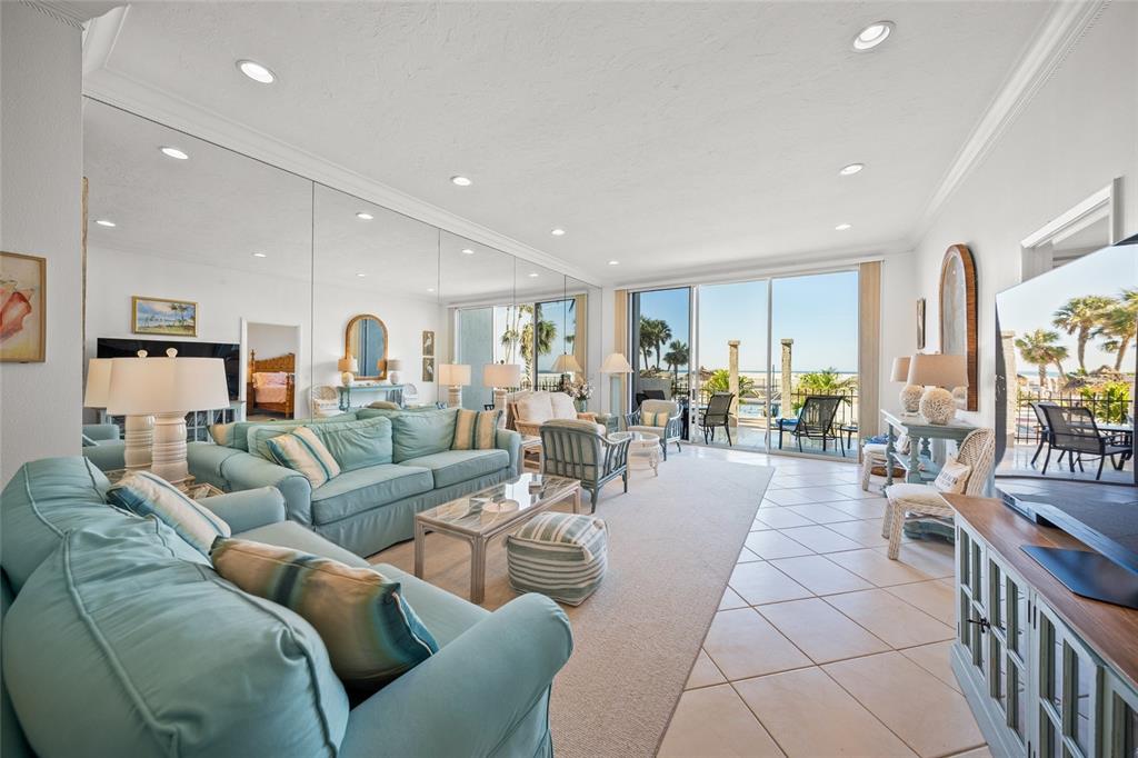 A living room with light blue sofas, mirrored walls, and sliding glass doors to a patio — 1212 BENJAMIN FRANKLIN DRIVE UNIT 102, SARASOTA, FL