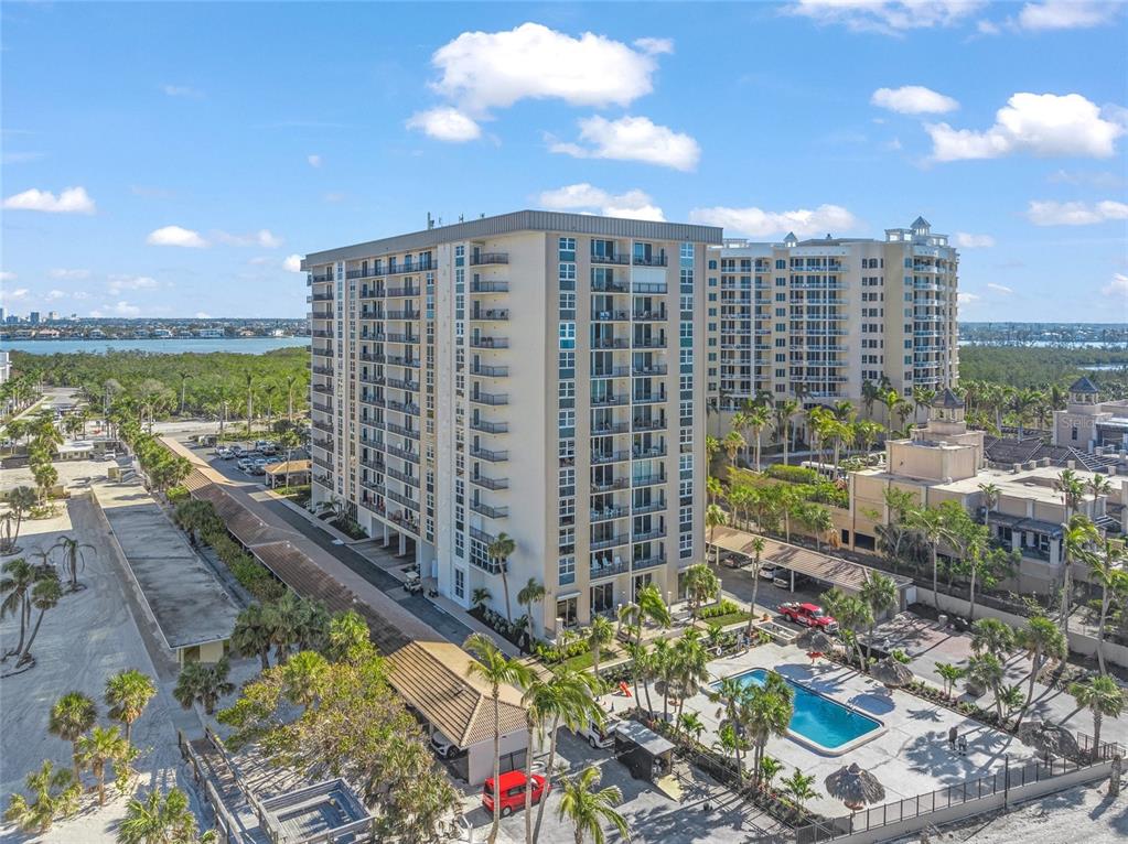 An aerial view shows two multi-story apartment buildings with a swimming pool and parking area — 1212 BENJAMIN FRANKLIN DRIVE UNIT 102, SARASOTA, FL
