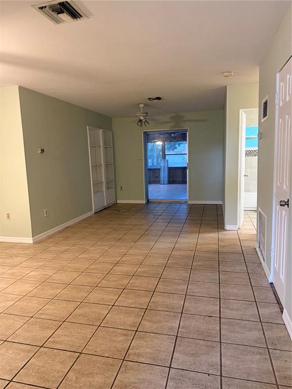 A room with light green walls, tan tile flooring, a ceiling fan, and a sliding door — 3543 BALI DRIVE, SARASOTA, FL