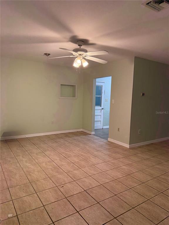 An interior view of a room with light green walls, tiled flooring, and a ceiling fan — 3543 BALI DRIVE, SARASOTA, FL
