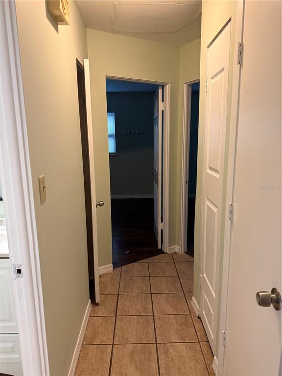 A hallway with tiled flooring leads to two doorways opening into a bedroom — 3543 BALI DRIVE, SARASOTA, FL