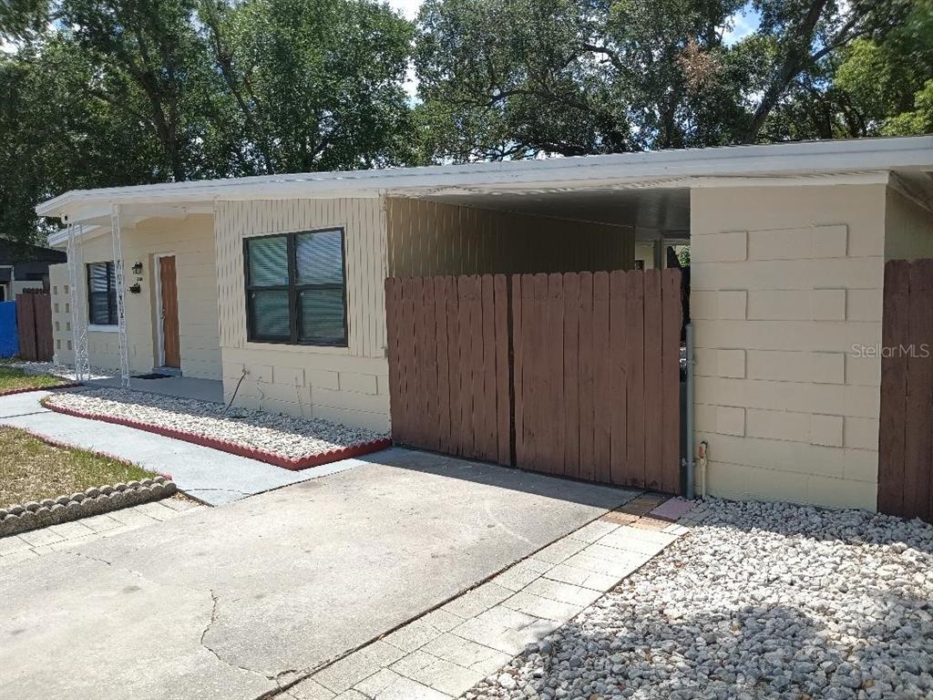A single-story house with a beige exterior, a carport, and a wooden privacy gate — 5700 CORTEZ DRIVE, ORLANDO, FL
