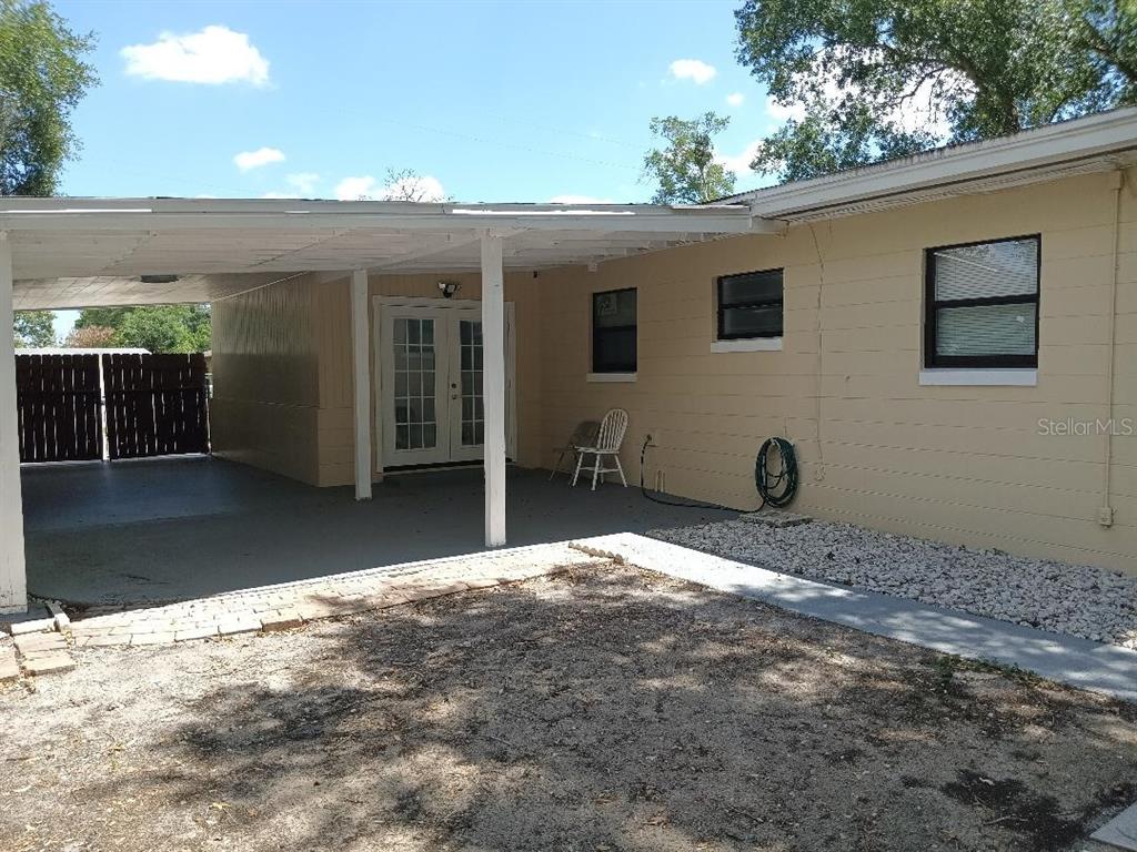 A beige house exterior features a covered carport, French doors, and a gravel yard — 5700 CORTEZ DRIVE, ORLANDO, FL