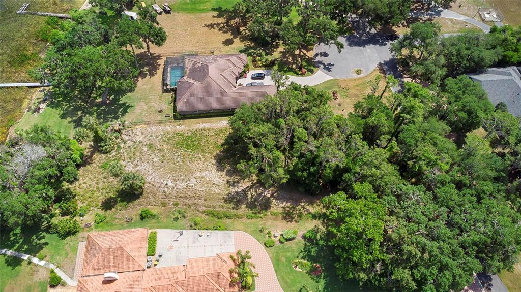 An aerial view shows two houses with pools and driveways surrounded by trees and grass — 713 NEWELL HILL ROAD, LEESBURG, FL