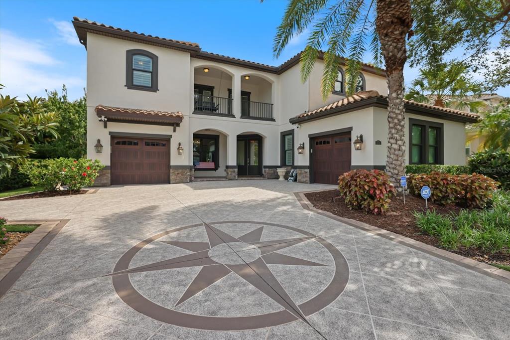 A two-story Mediterranean-style house features a stamped concrete driveway with a large compass rose design — 1711 KENILWORTH STREET, SARASOTA, FL