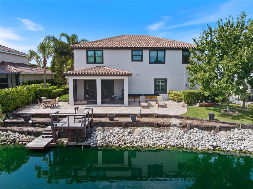A two-story house with a screened patio, stone terrace, and wooden dock overlooking a canal — 1711 KENILWORTH STREET, SARASOTA, FL