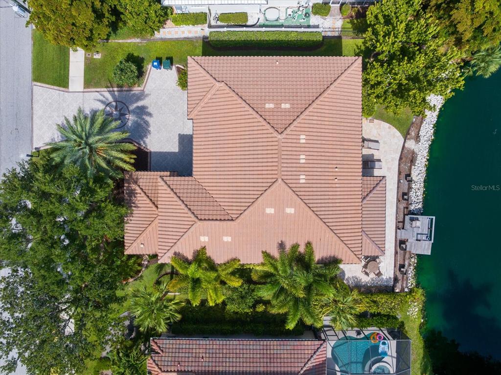 An aerial view shows a house with a tiled roof, driveway, and waterfront backyard — 1711 KENILWORTH STREET, SARASOTA, FL