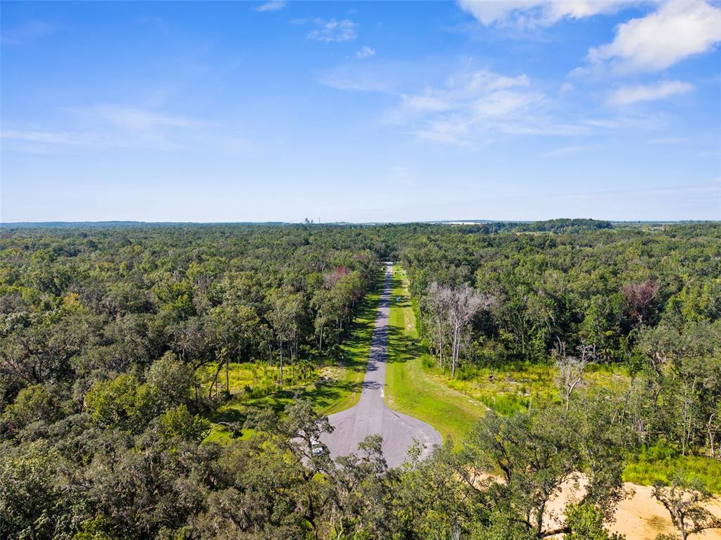 An aerial view shows a paved cul-de-sac road extending into a dense, forested landscape — REPUBLICAN (LOT 6) WAY, BROOKSVILLE, FL