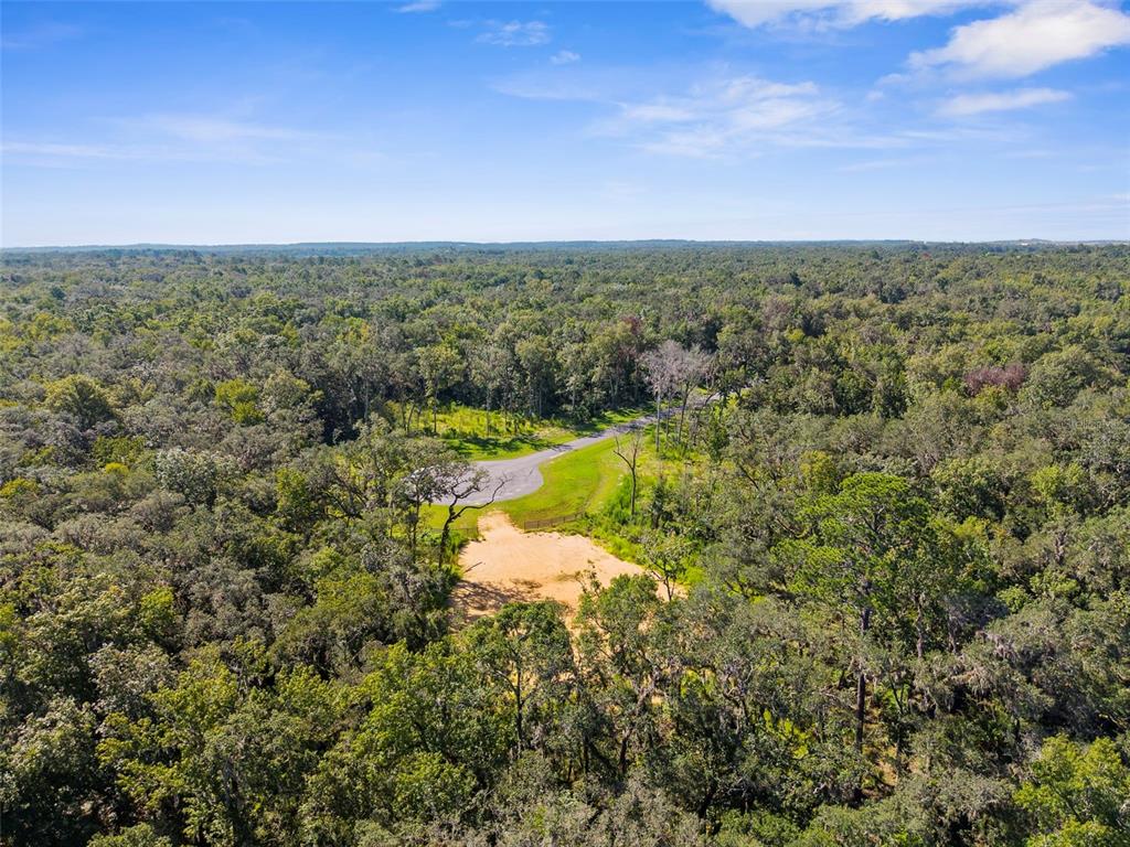 An aerial view shows a sandy clearing surrounded by dense forest with a paved road — REPUBLICAN (LOT 6) WAY, BROOKSVILLE, FL