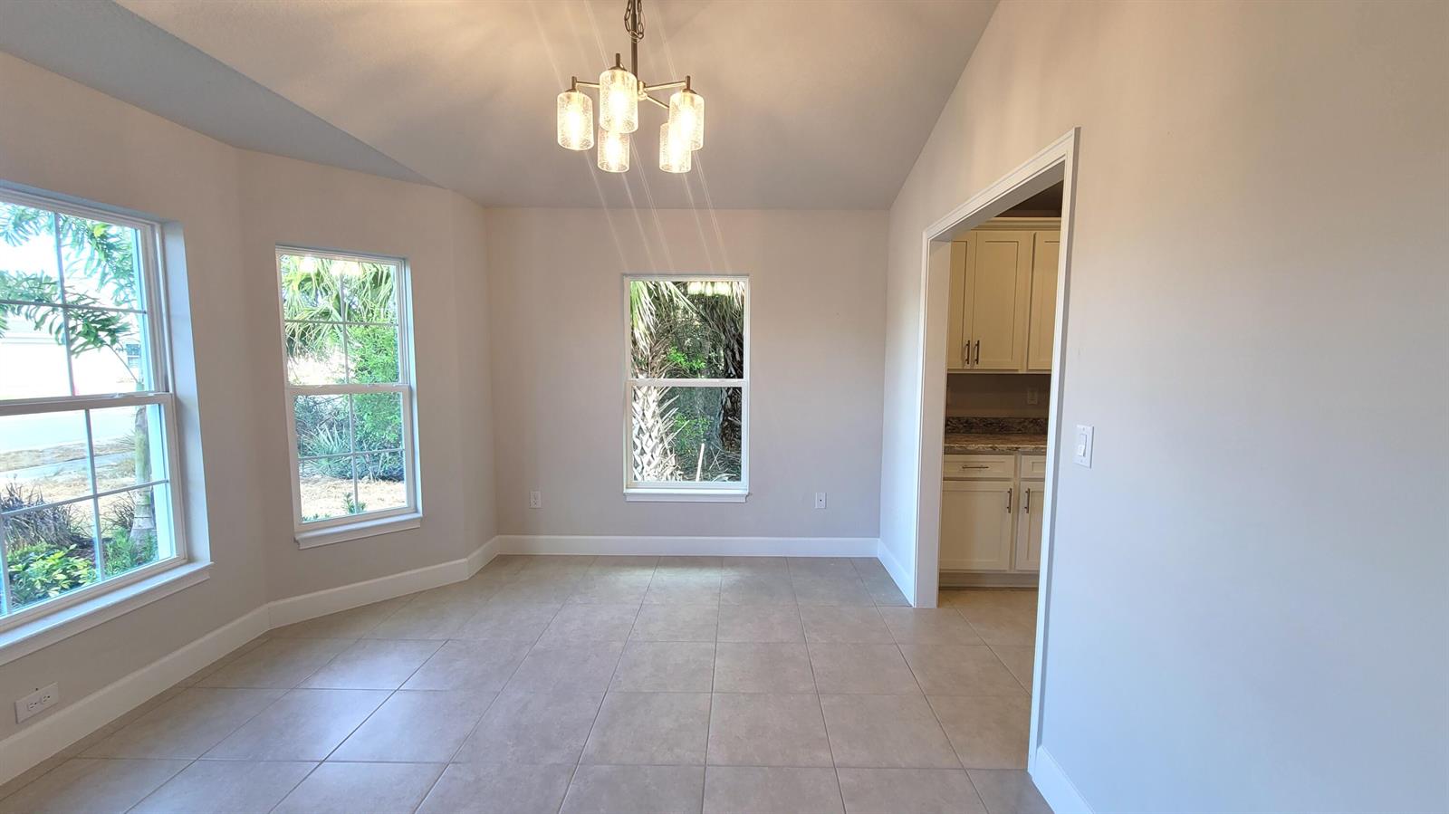An empty dining area features tile flooring, a chandelier, and windows overlooking outdoor greenery — 8844 Waterstone Boulevard, Fort Pierce FL 34951, FORT PIERCE, FL