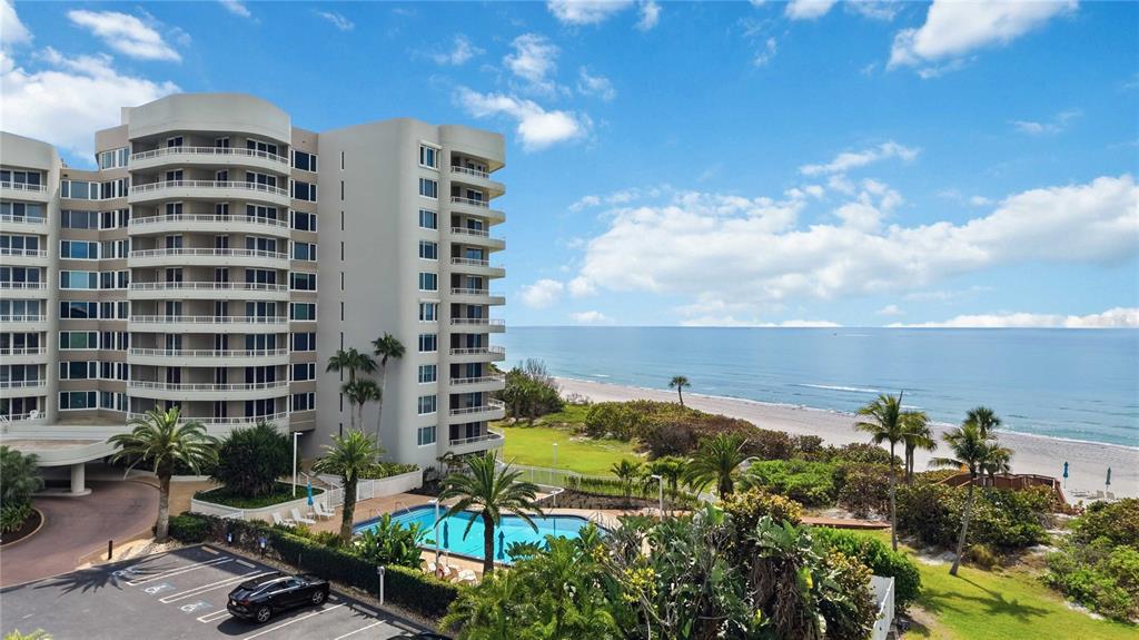 An exterior view of a multi-story apartment building with a swimming pool and oceanfront beach — 775 LONGBOAT CLUB ROAD UNIT 401, LONGBOAT KEY, FL