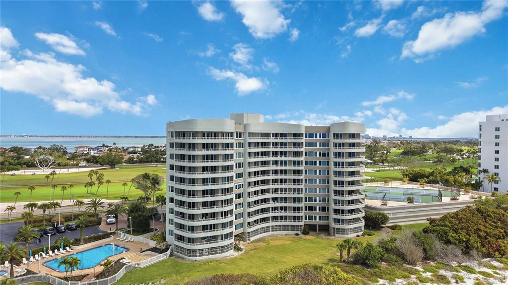 An aerial view shows a multi-story residential building with a pool, tennis courts, and golf course — 775 LONGBOAT CLUB ROAD UNIT 401, LONGBOAT KEY, FL