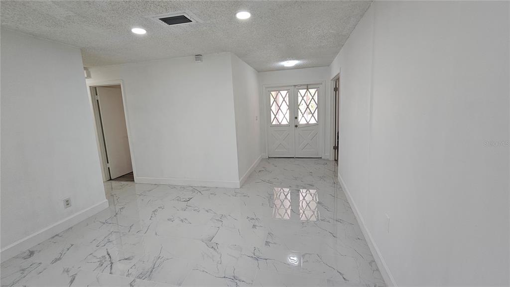 An interior view shows a room with white walls, recessed lighting, and white marble-patterned tile flooring — 2626 WENDOVER TERRACE, PALM HARBOR, FL
