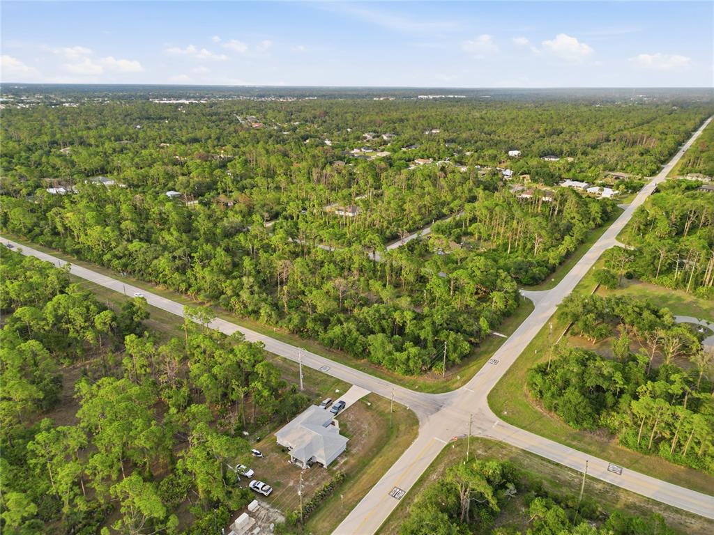 An aerial view shows a rural intersection surrounded by dense forest and scattered residential homes — 501 CHAMPION ST DRIVE, PORT CHARLOTTE, FL