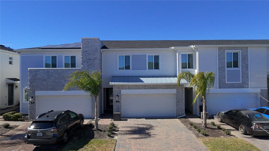 A two-story townhouse exterior features a stone facade, a paved driveway, and palm trees — 176 BOGEY DRIVE, DAVENPORT, FL