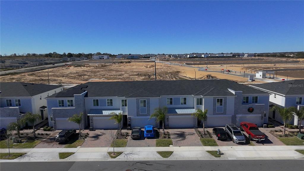 An aerial view shows a row of modern townhouses with garages facing a paved street — 176 BOGEY DRIVE, DAVENPORT, FL
