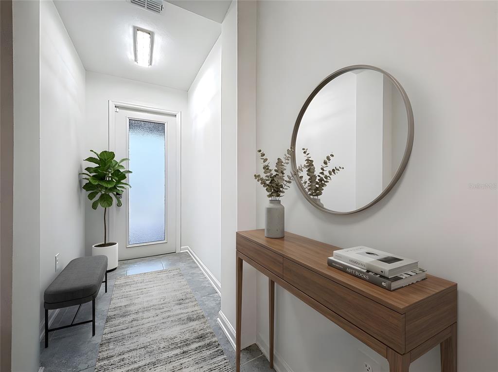 A bright entryway features a gray bench, a wooden console table, and a round mirror — 176 BOGEY DRIVE, DAVENPORT, FL