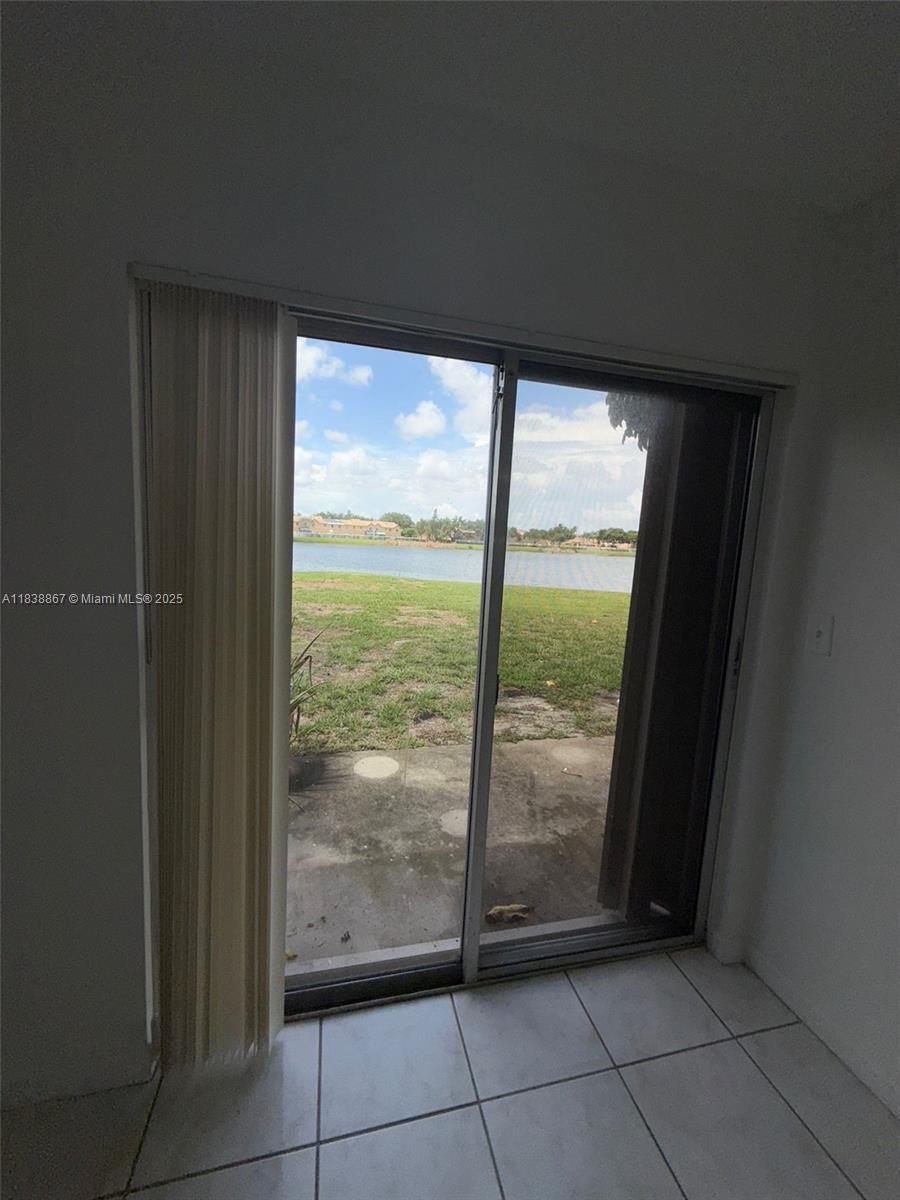 A sliding glass door opens to a patio overlooking a lake and grassy yard — 8560 N Sherman Cir # 105, Miramar FL 33025, MIRAMAR, FL