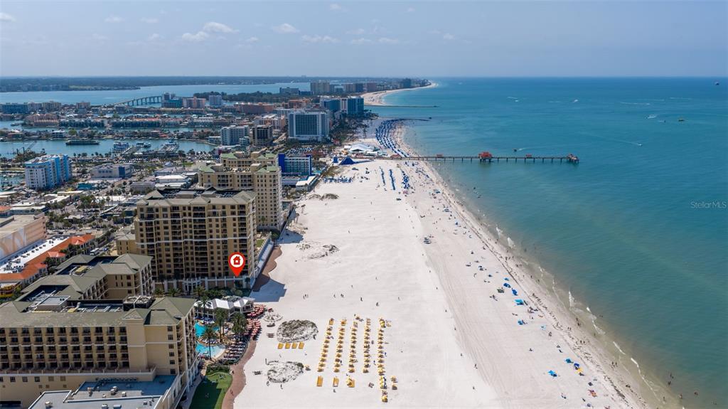 An aerial view shows a high-rise hotel building situated directly on a sandy beach — 11 BAYMONT STREET UNIT 302, CLEARWATER BEACH, FL